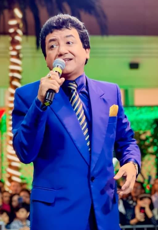 Carlos Burga, Yo Soy José José, con traje azul y micrófono en concierto