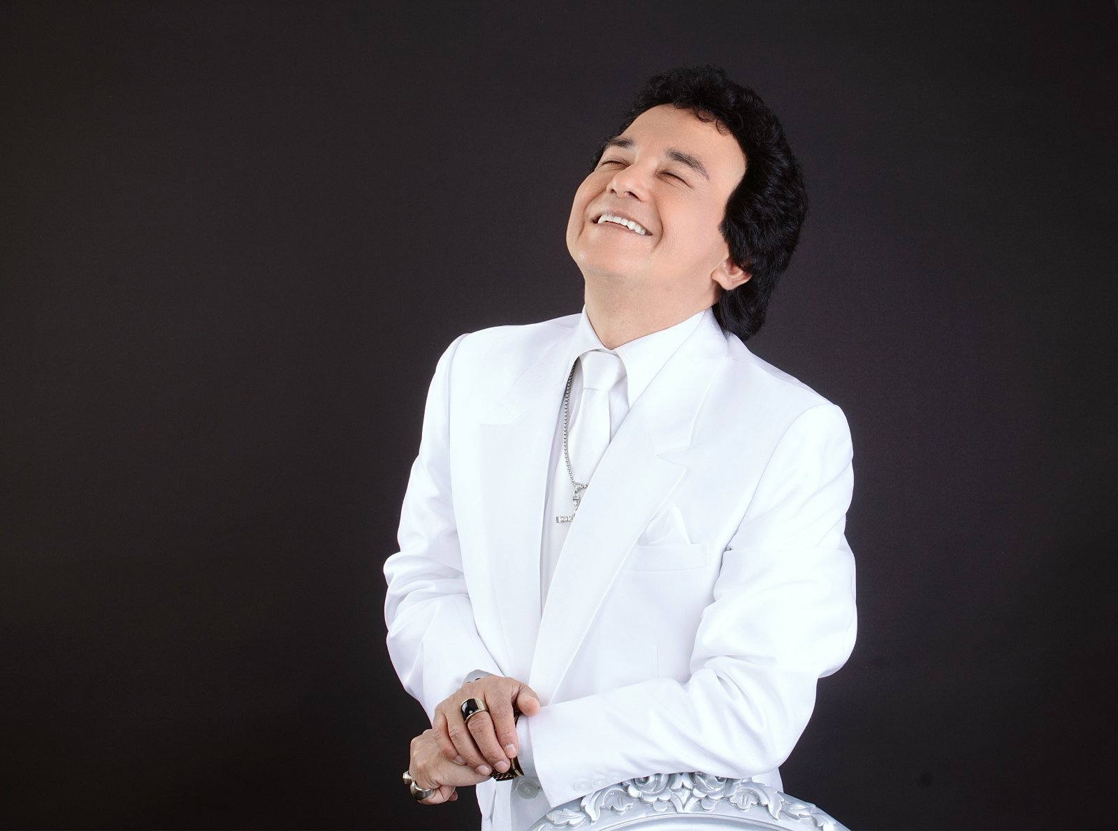Carlos Burga, Yo Soy José José, sonriendo con traje blanco en sesión de estudio