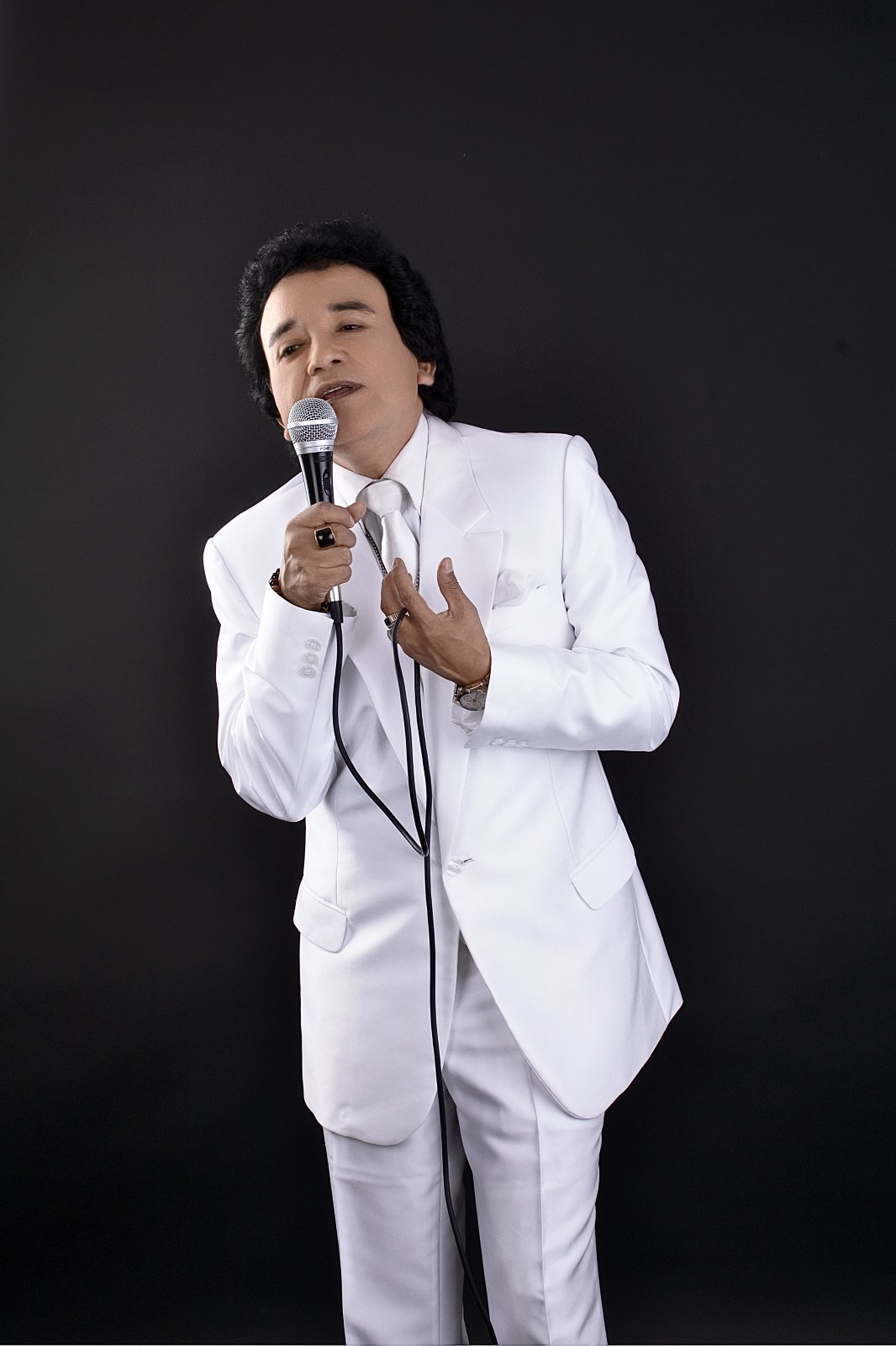 Carlos Burga cantando como José José con traje blanco y micrófono